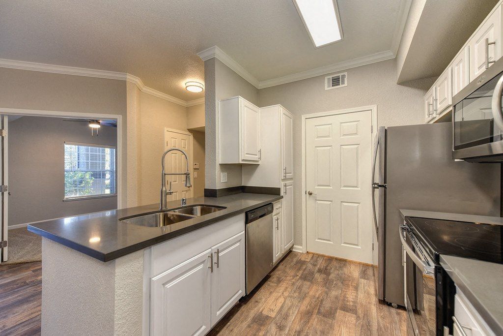 Bright apartment kitchen with an island, double sink, and stainless steel appliances at River Oaks.