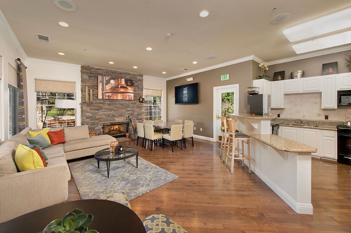 Spacious open-concept living area with a stone fireplace, dining table, kitchen, and seating at River Oaks.