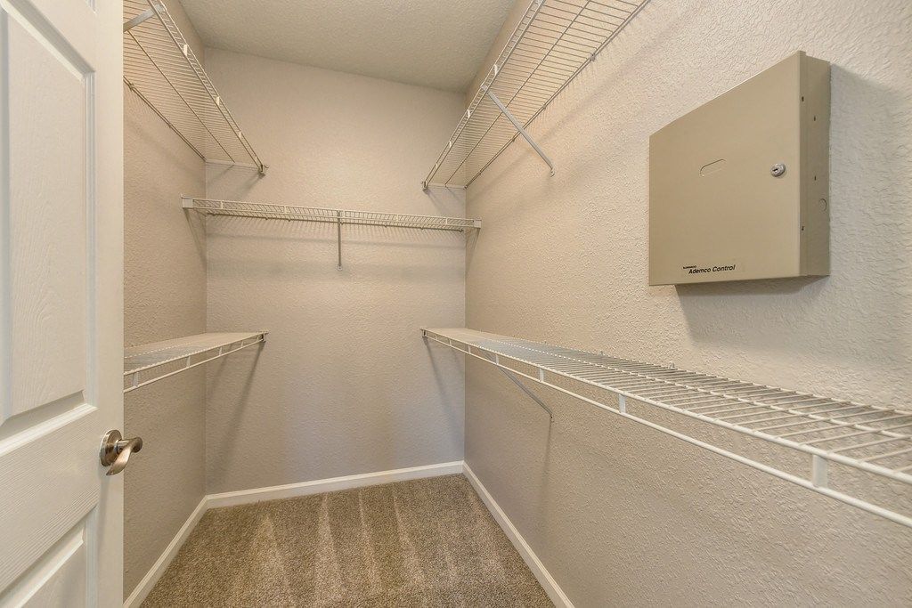 Walk-in closet with white wire shelves and beige walsl at River Oaks.