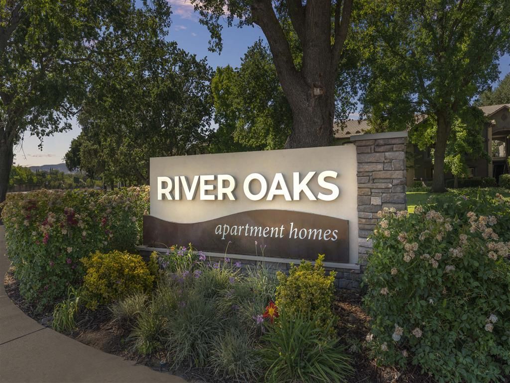 Exterior entrance sign for River Oaks apartment homes with landscaping at River Oaks.