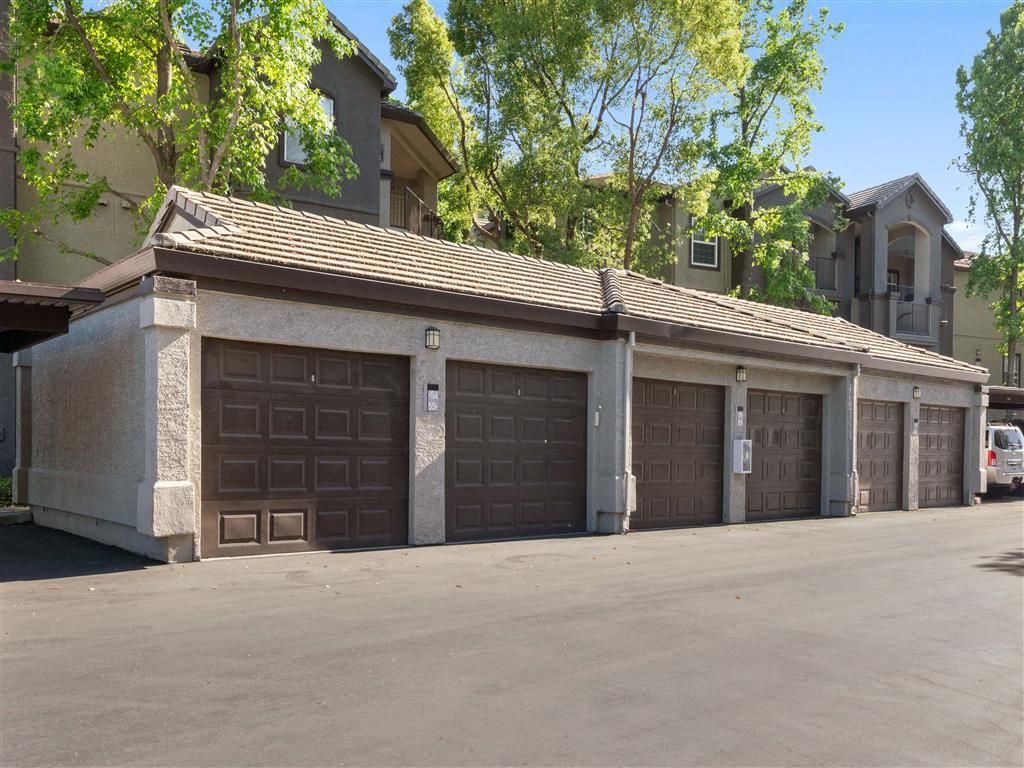 Row of brown garage doors at a multi-family complex with trees above at River Oaks.