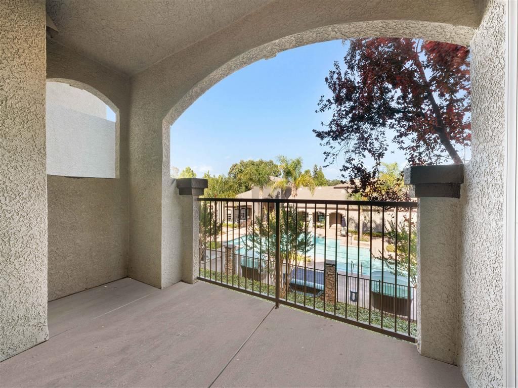 Balcony with railing overlooking a communal pool in an apartment community at River Oaks.