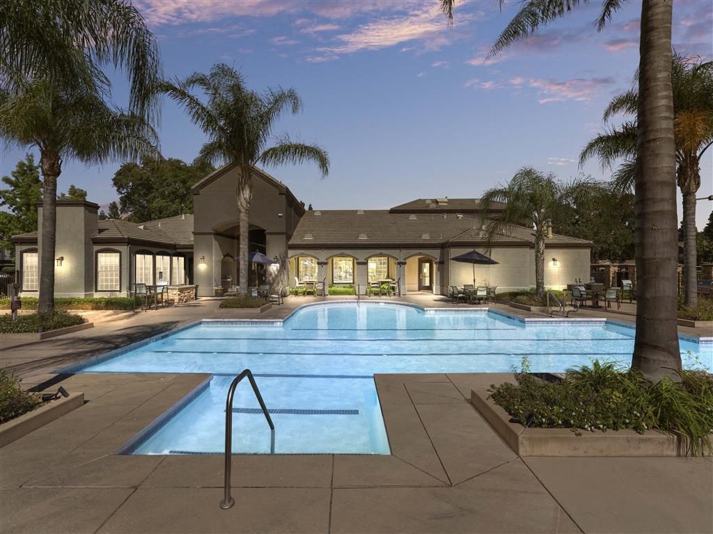 Outdoor pool at a residential community with palm trees and seating areas at River Oaks.