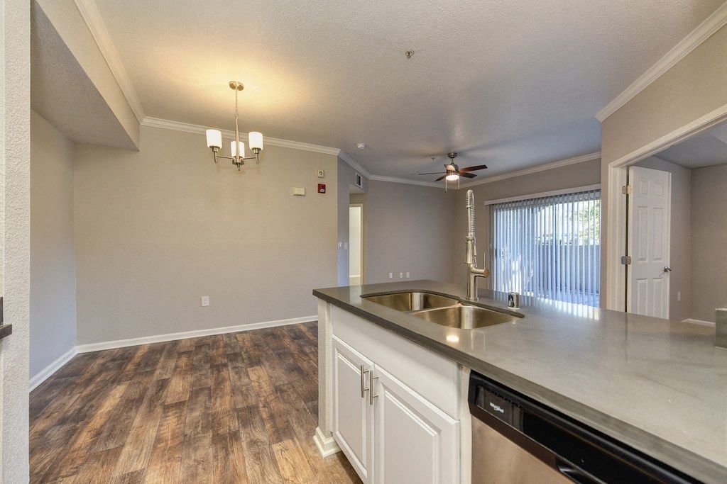 Open-concept apartment kitchen with island, double sink, and laminate flooring at River Oaks.