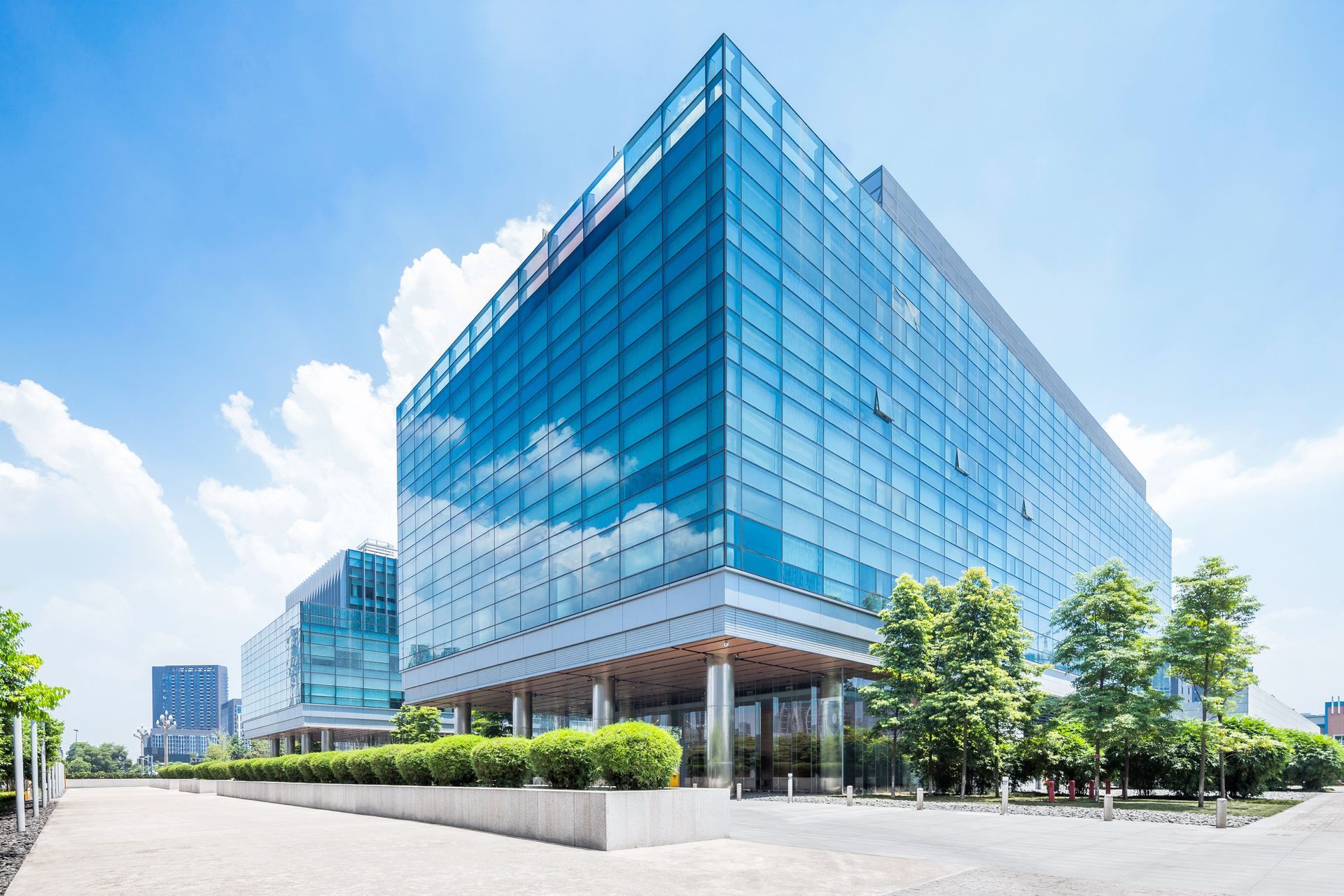 A large glass building with a lot of windows and trees in front of it.