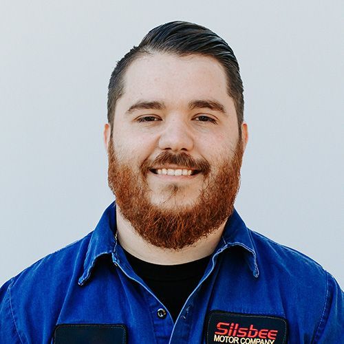 A man with a beard is wearing a blue shirt and smiling.