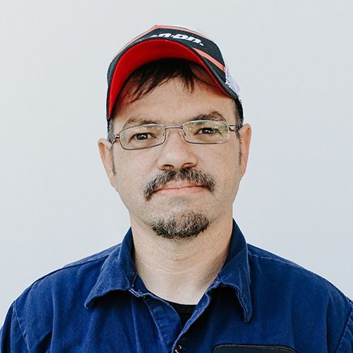 A man wearing a hat and glasses is looking at the camera