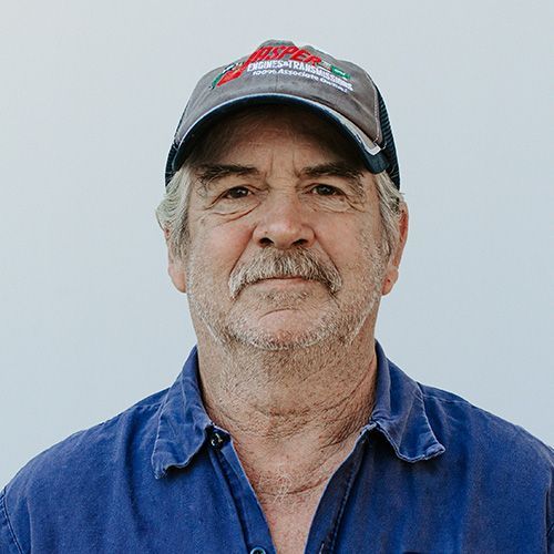 A man wearing a hat and a blue shirt is looking at the camera.