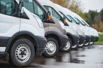 A row of vans parked next to each other in a parking lot.