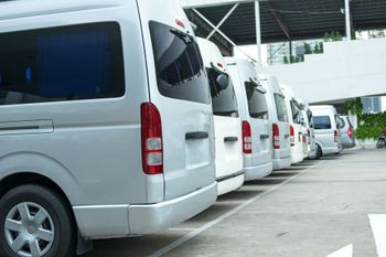A row of white vans are parked in a parking lot.