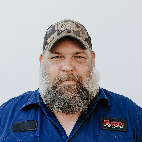 A man with a beard is wearing a hat and a blue shirt.