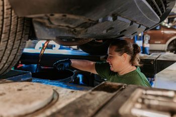 A close up of a person pouring oil into a car engine.