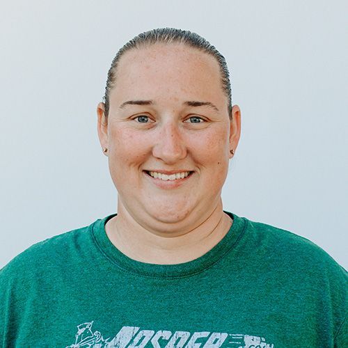 A woman wearing a green shirt is smiling for the camera.