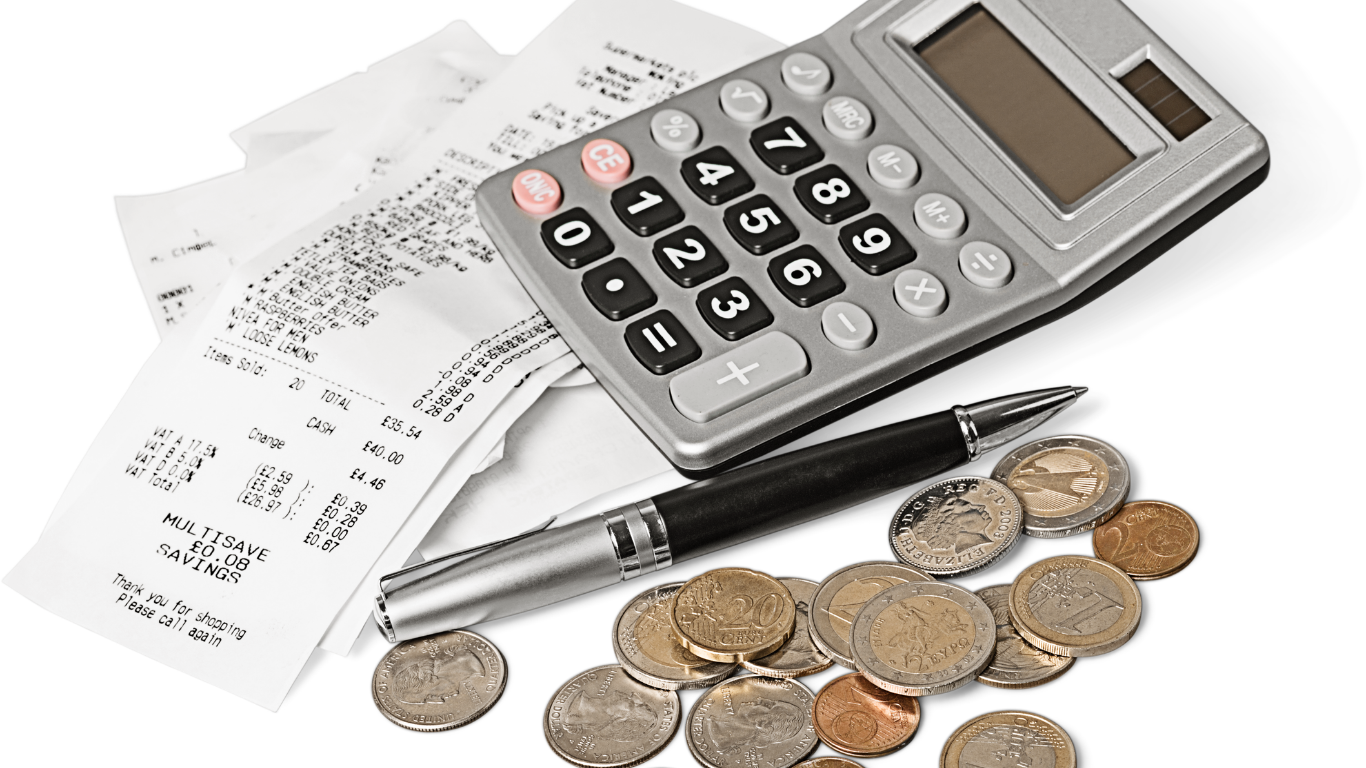 Calculator, receipts, pen, and scattered coins on a white surface, suggesting budgeting or expense tracking