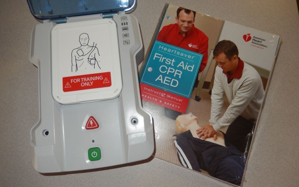 A first aid cpr aed is sitting next to a book