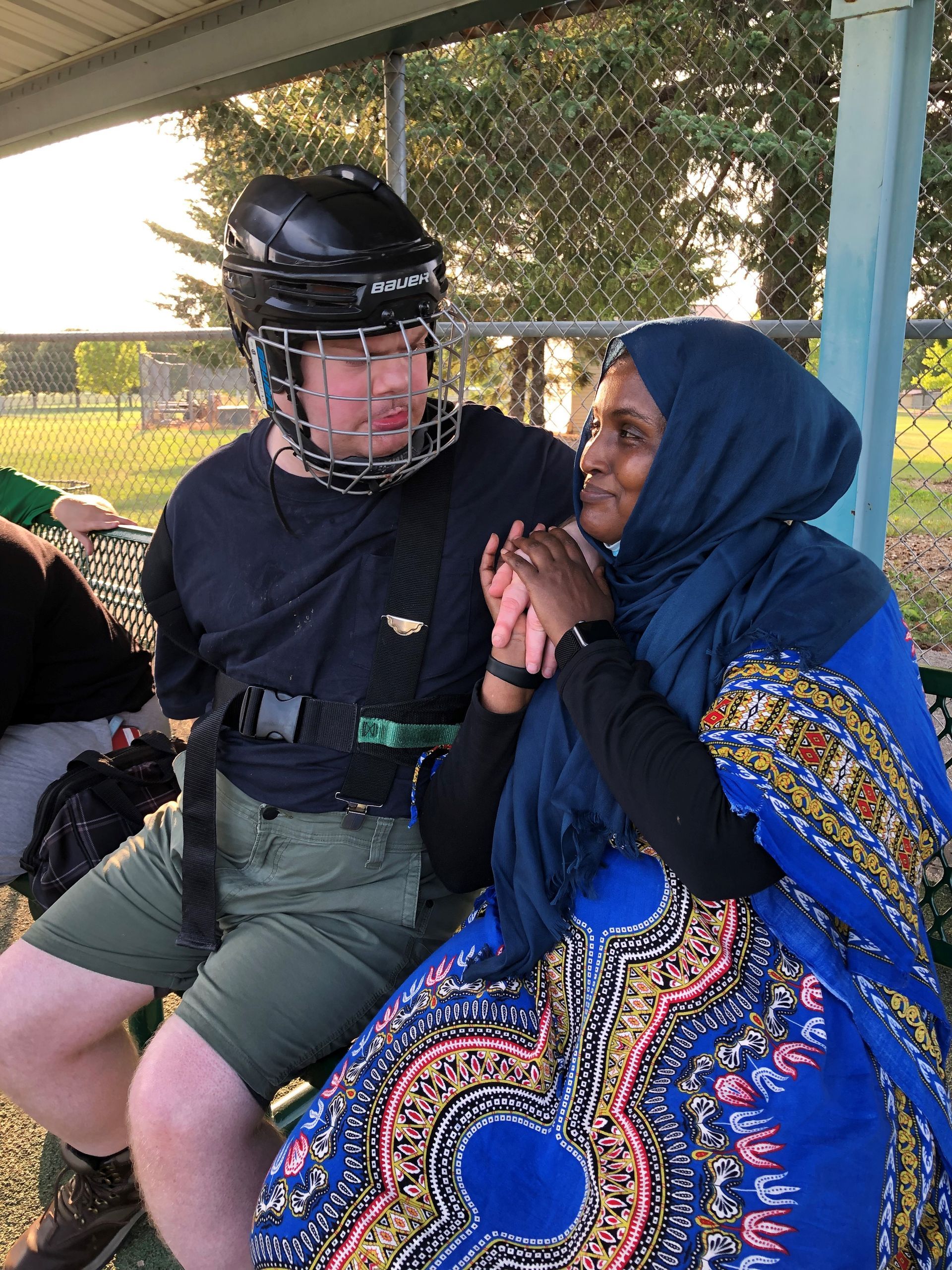 A man wearing a helmet is sitting next to a woman wearing a hijab.