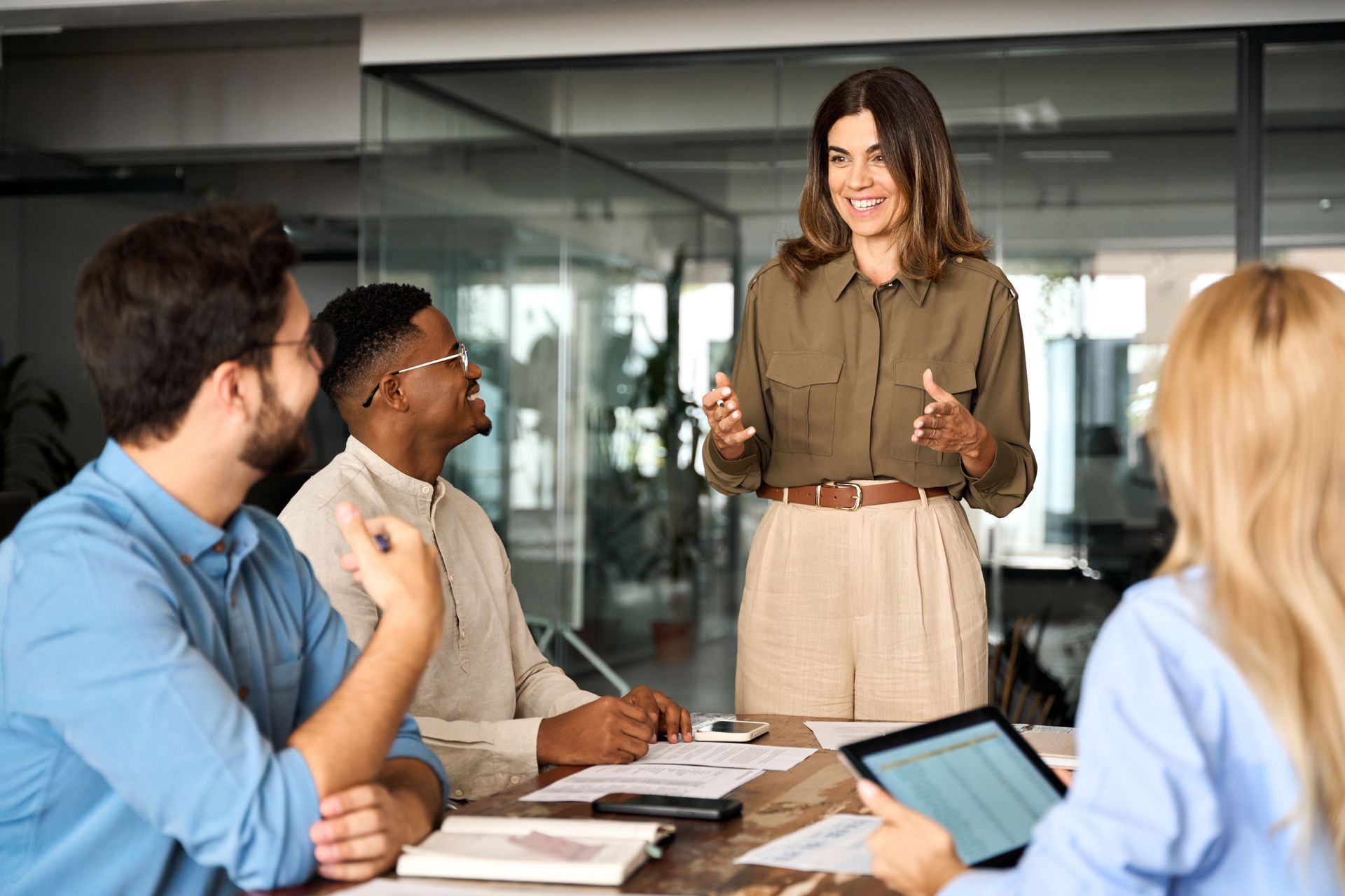 Colleagues in a conference room listening to a woman presenting at the front.