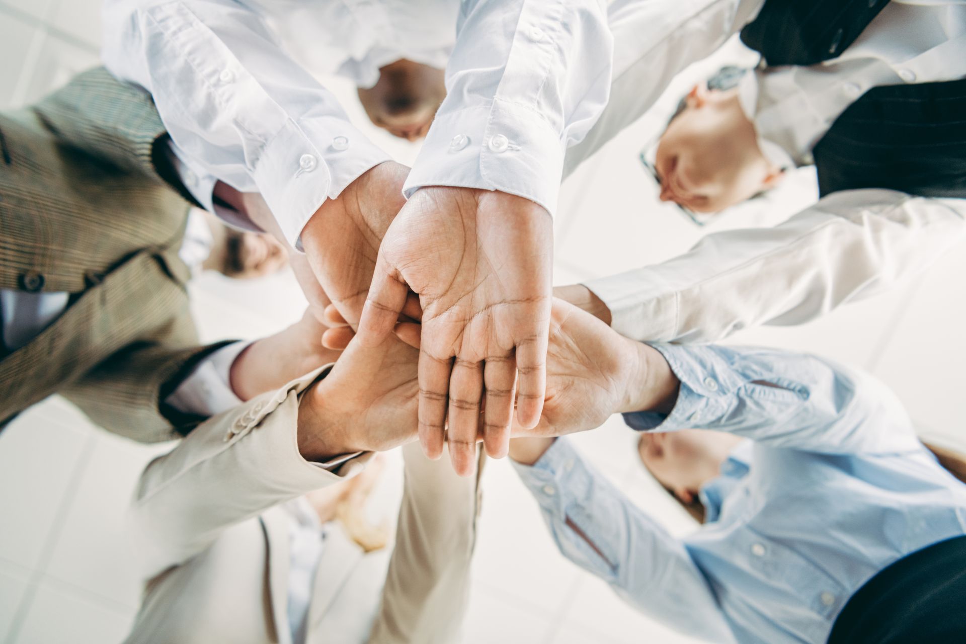 Une équipe de personnes se tenant la main en cercle, symbolisant le travail d'équipe et l'unité.
