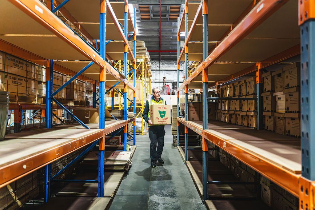 View of the interior of a warehouse with a man with a box in his hands.