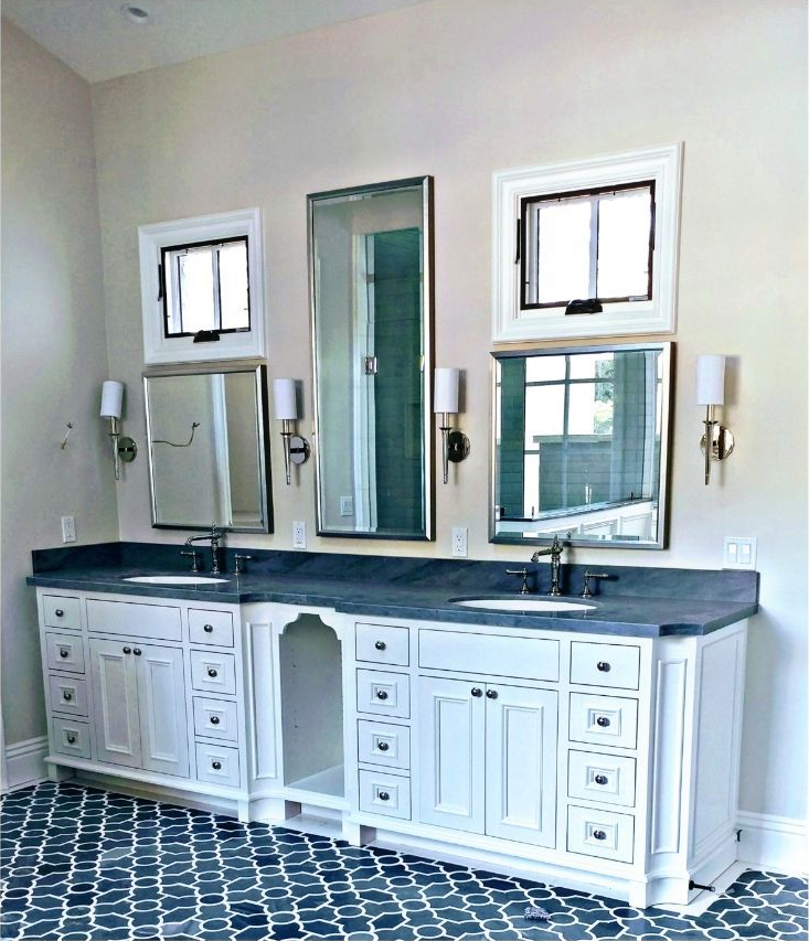 Bathroom with white vanity, blue countertop, and ornate blue-tiled floor. Three mirrors and sconces.