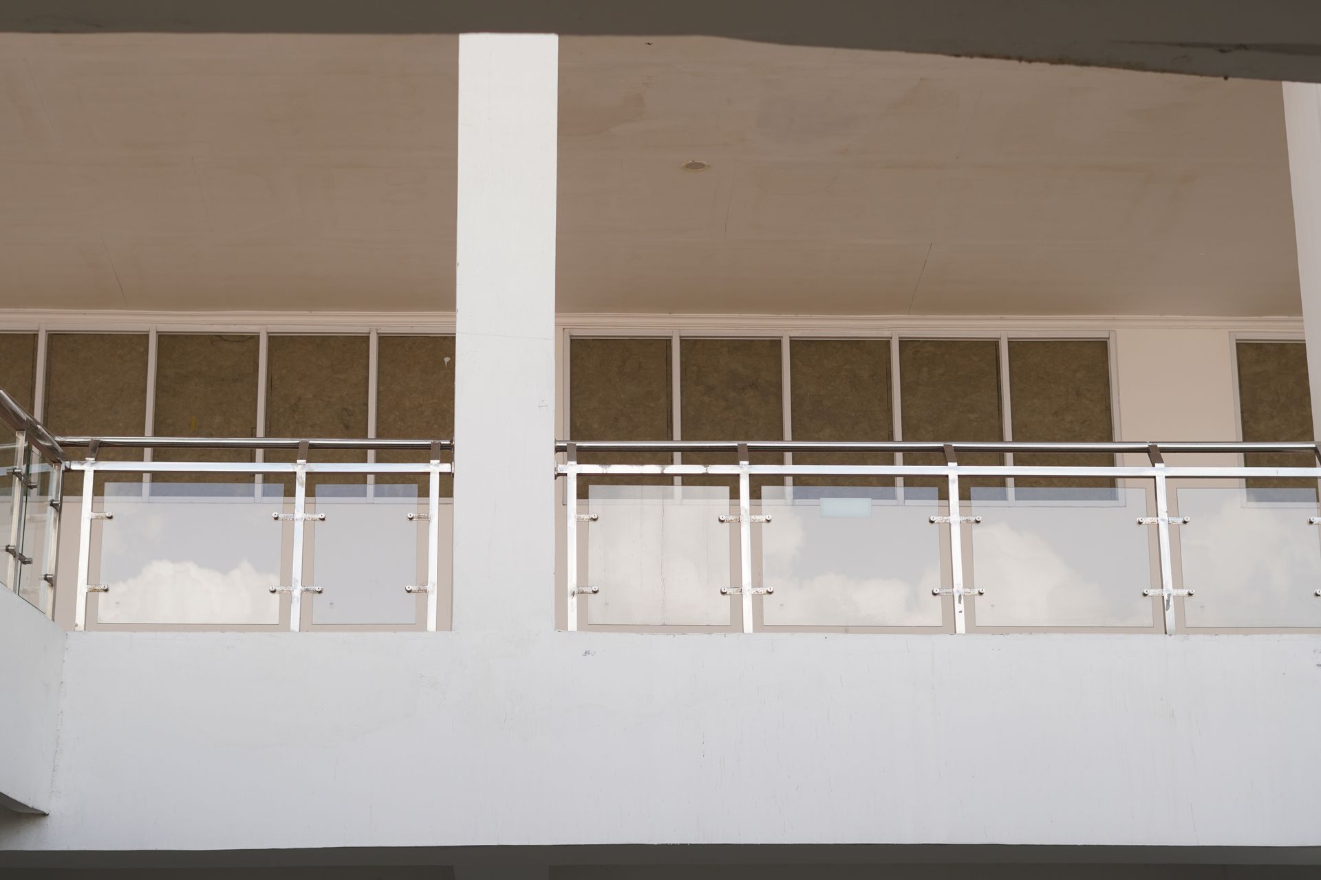 Building balcony with white railings and pillars under a beige ceiling
