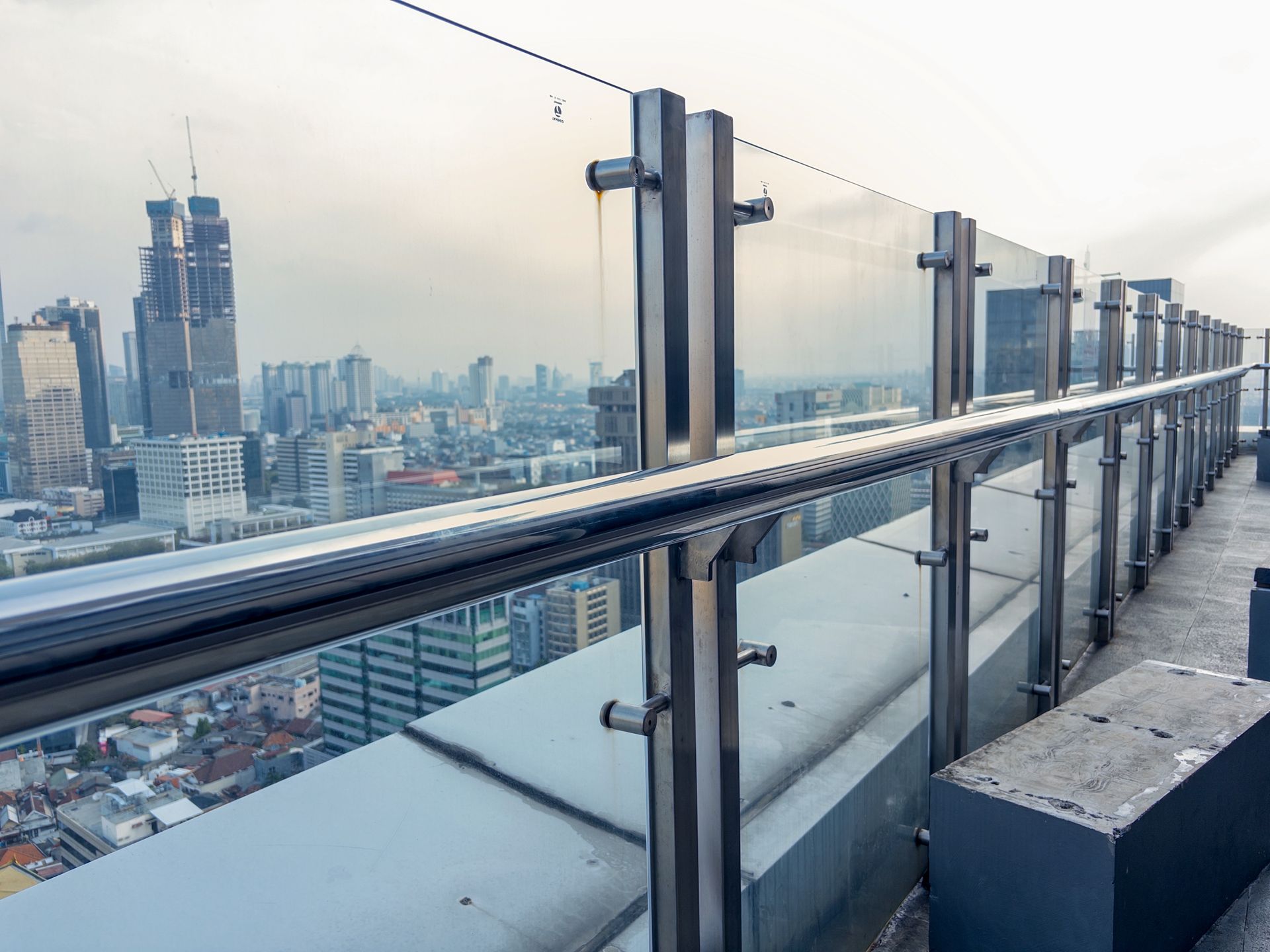 Rooftop observation deck with glass railing overlooking a city skyline at dusk