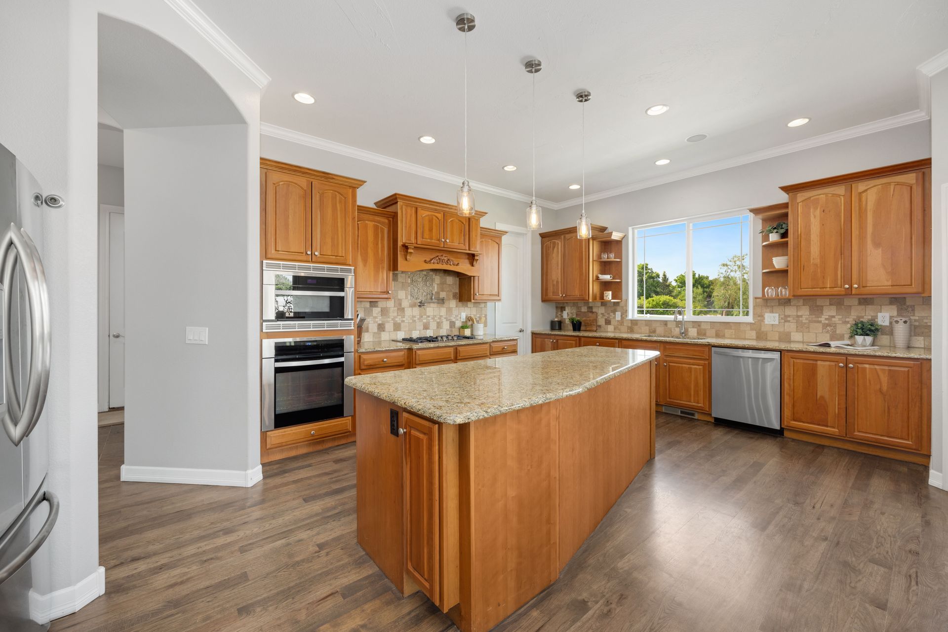 Bright modern kitchen with wood cabinets, granite island, stainless appliances, and large window