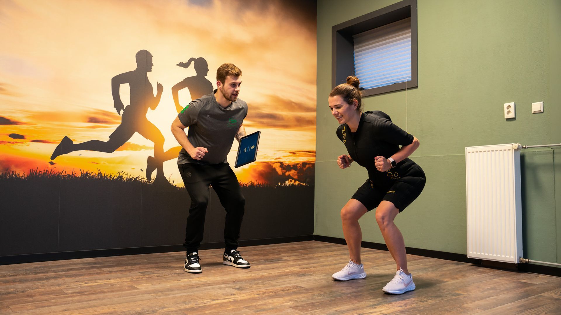 Een man en een vrouw doen squats in een sportschool.