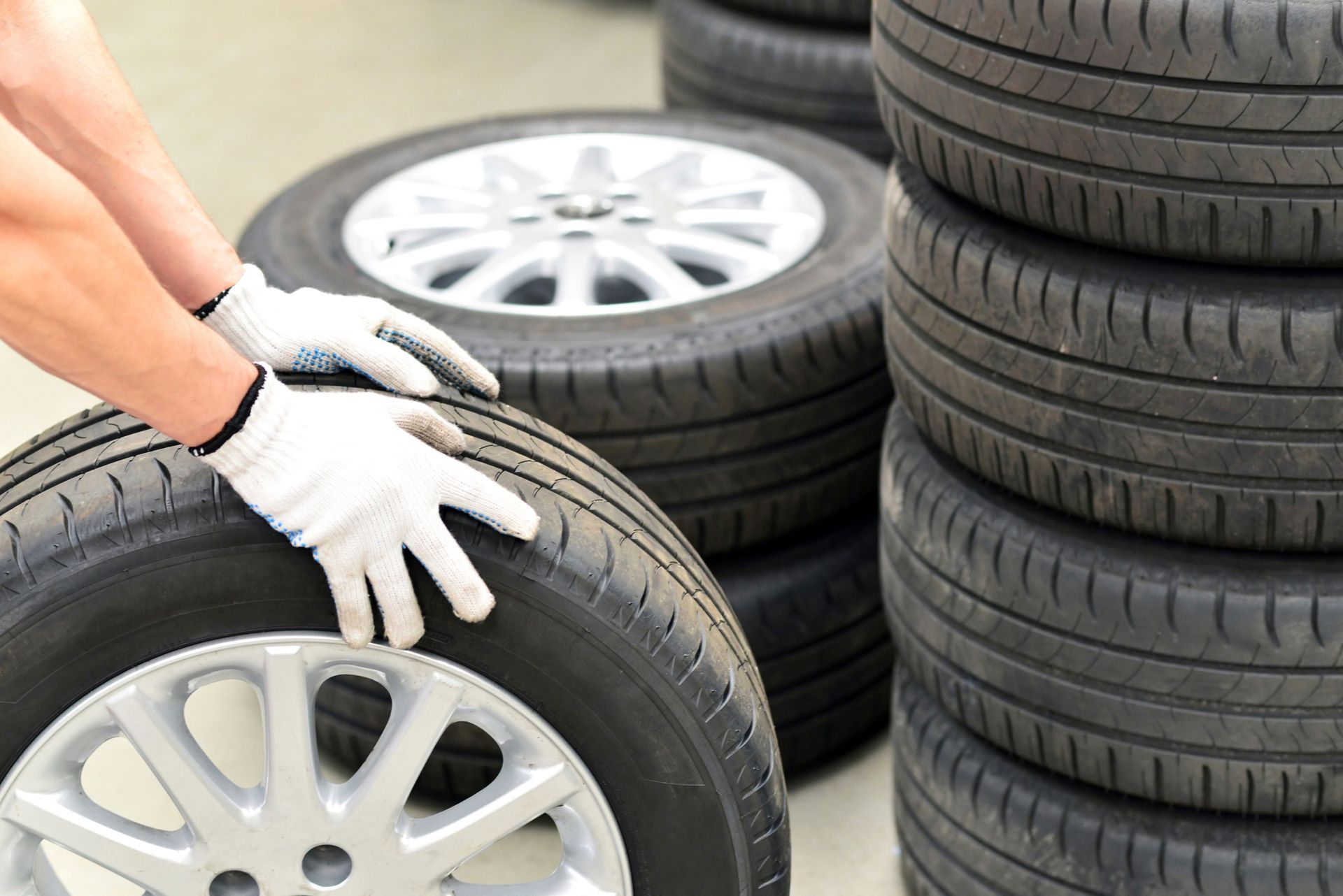 A person is holding a tire in front of a pile of tires. | Ruckersville, VA | KEL-CAM Tire & Auto