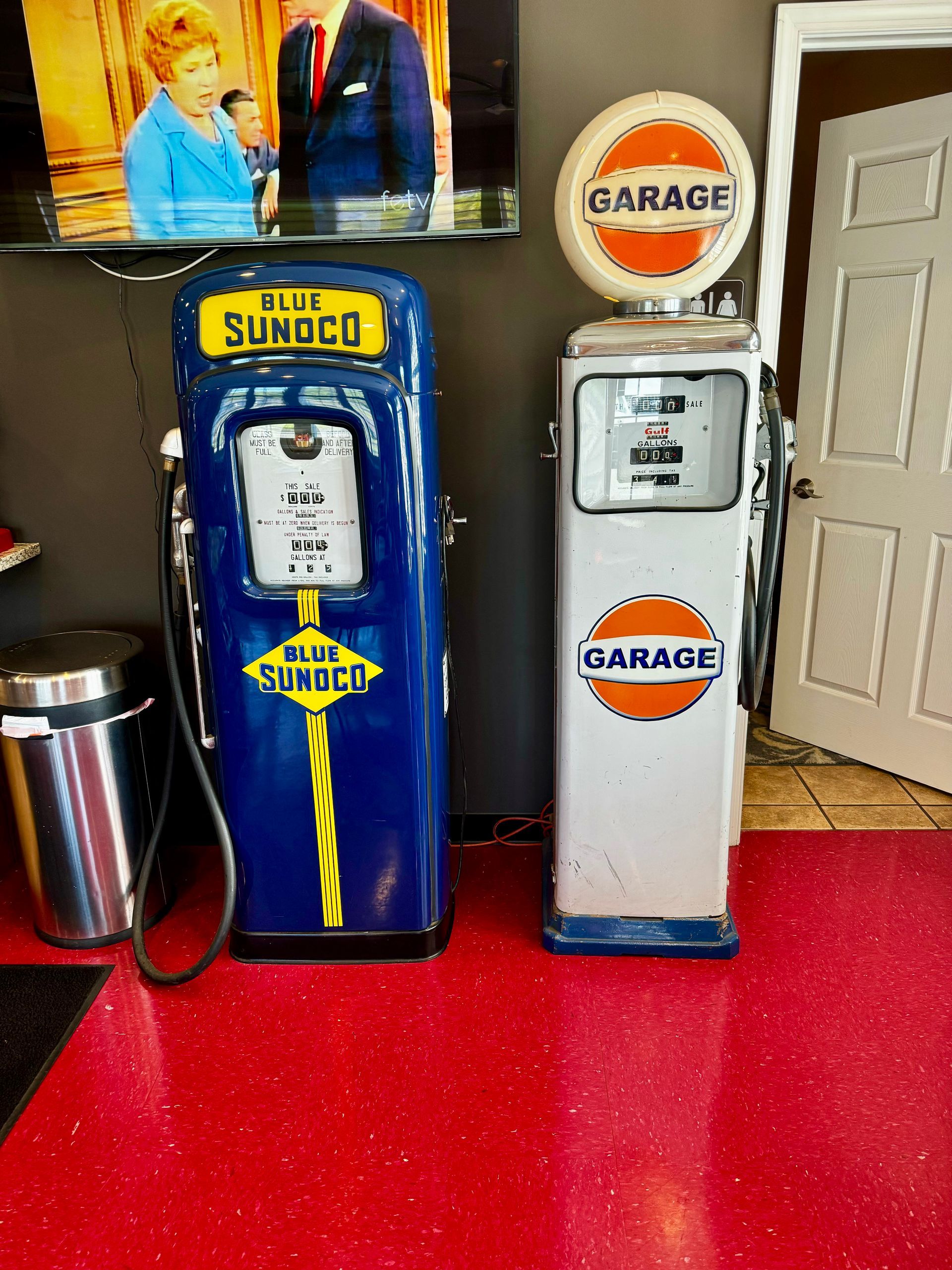A blue sunoco gas pump is next to a white garage gas pump