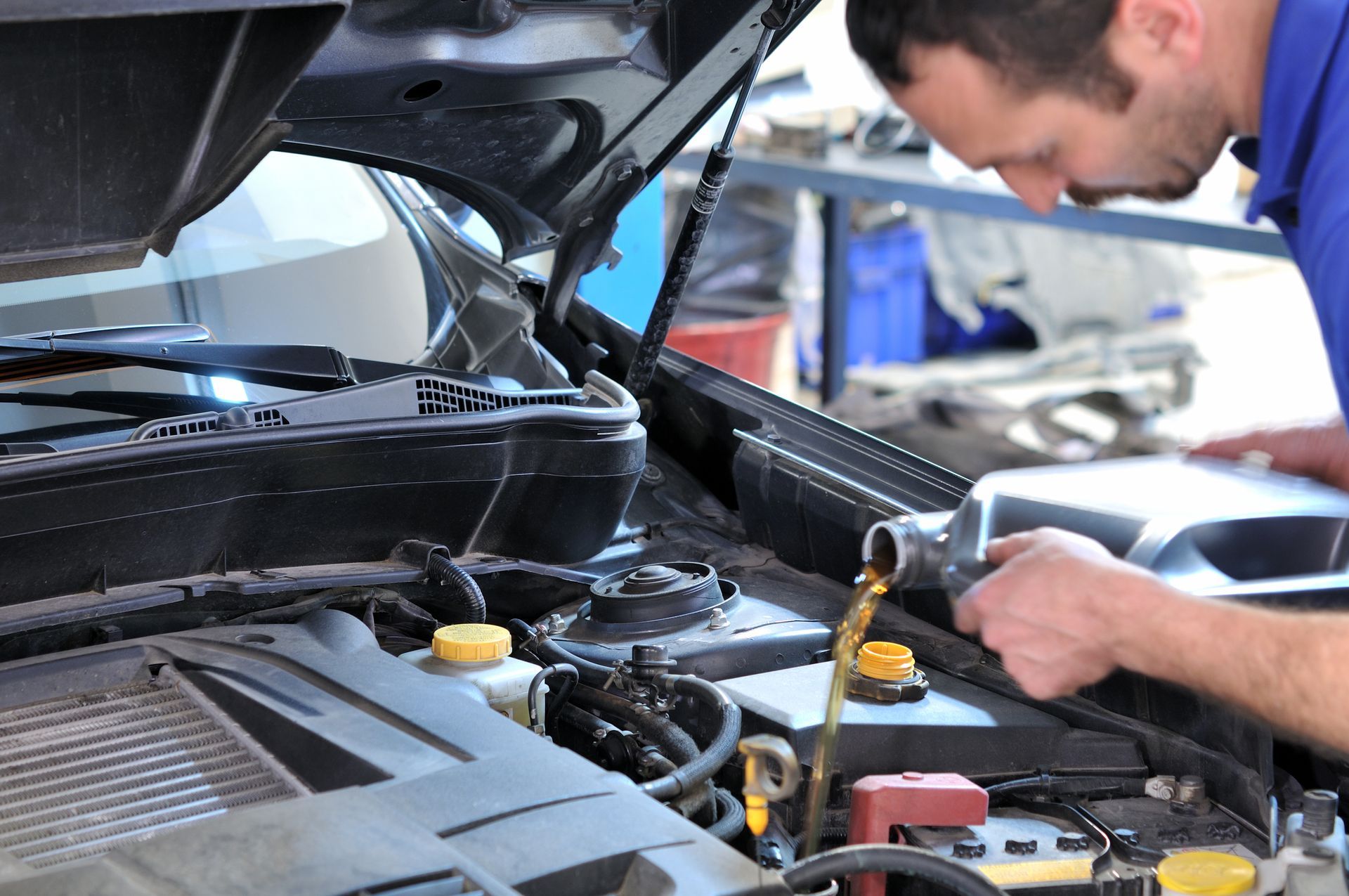 A man is pouring oil into a car engine. | Ruckersville, VA | KEL-CAM Tire & Auto