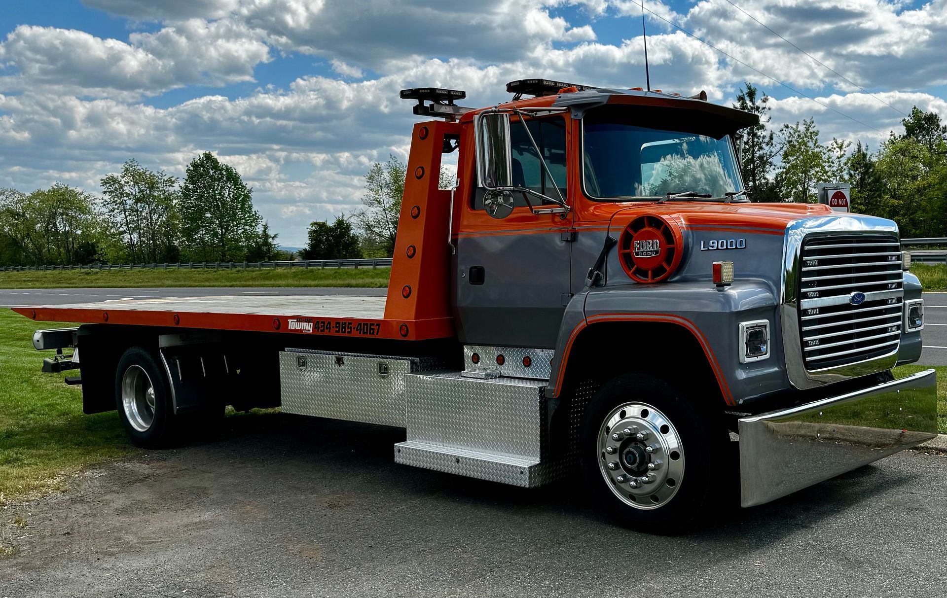 An orange and gray tow truck is parked on the side of the road.
