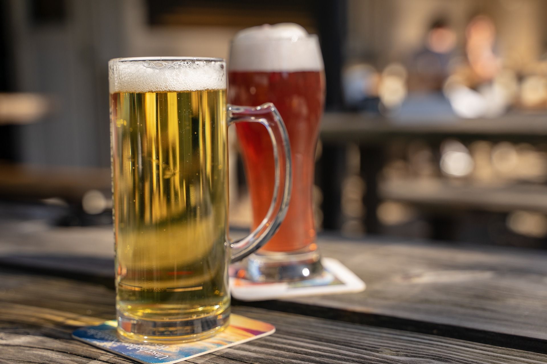 Due boccali di birra sono seduti su un tavolo di legno.