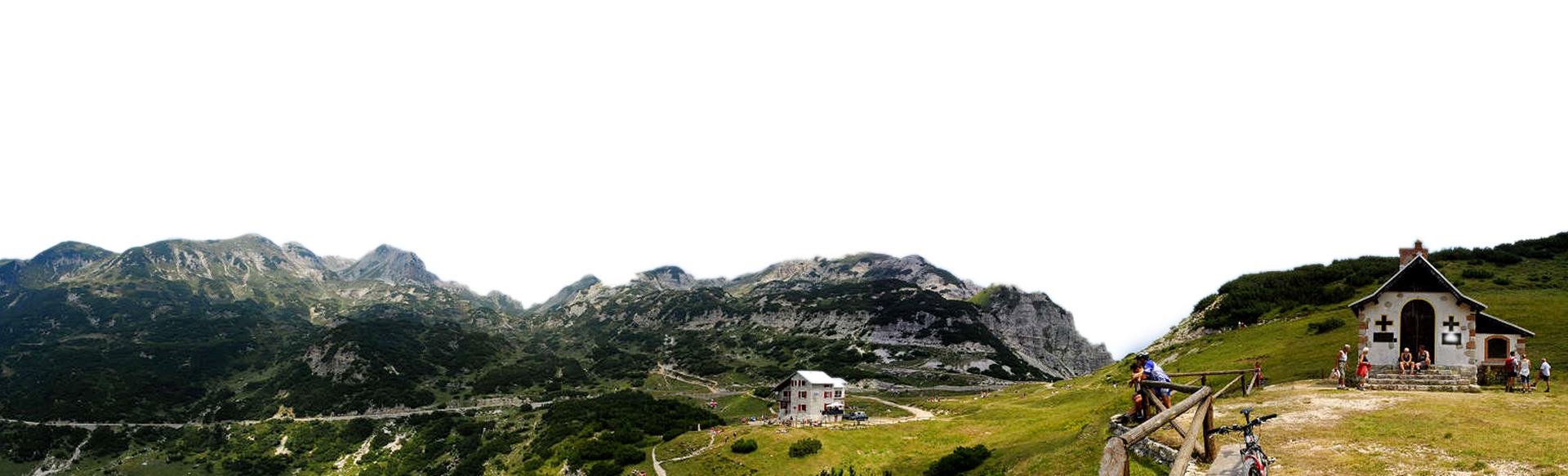 Una piccola casa bianca è situata in cima ad una collina erbosa circondata da montagne.