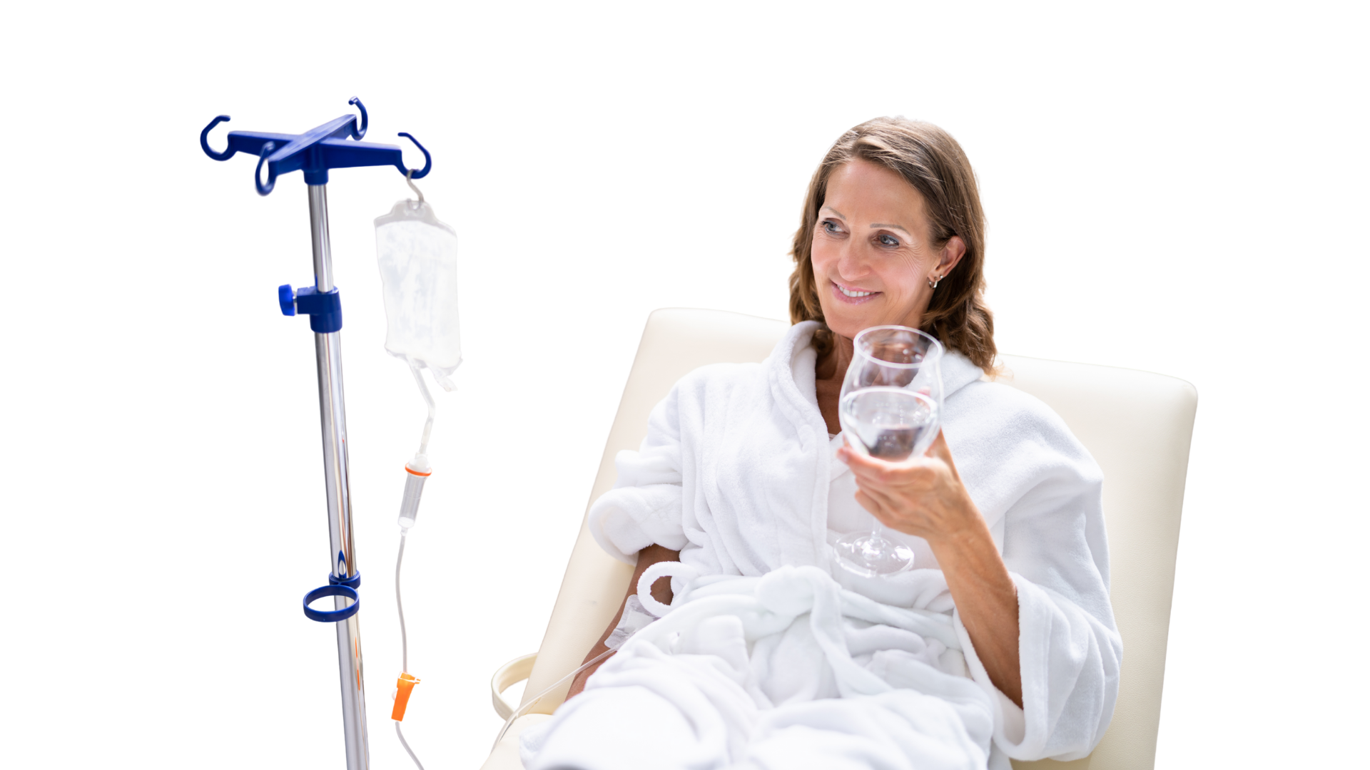 Woman in bathrobe sits with IV drip, holding water glass, smiling.
