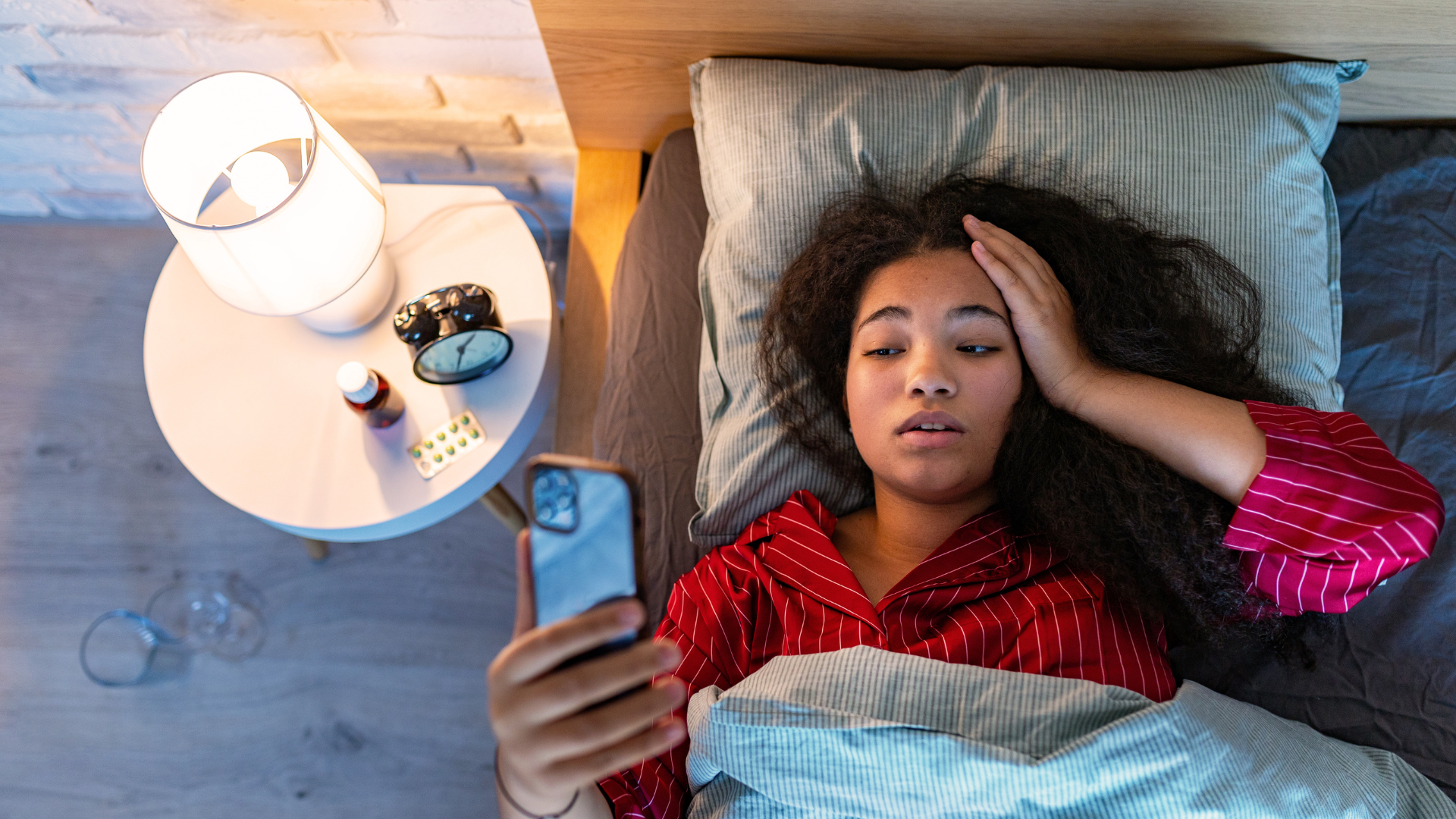 A woman is laying in bed looking at her phone.