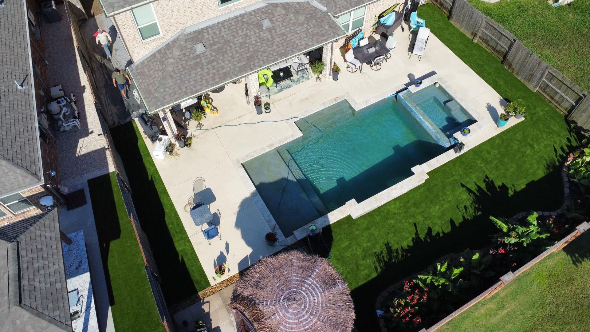 Aerial view of a home with a pool, patio, and green lawn.