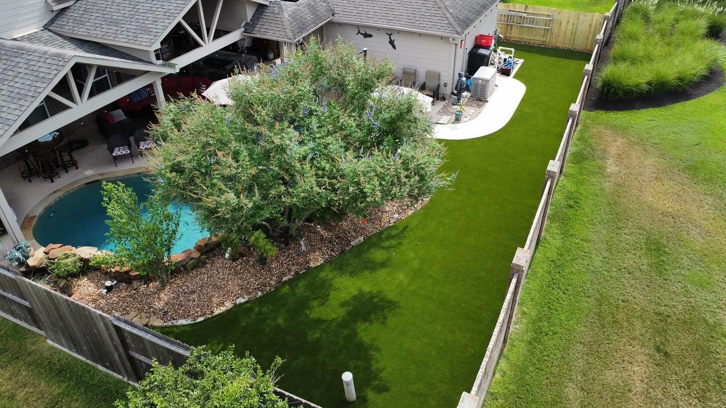 Aerial view of a home with a pool, lush green lawn, and wooden fence.