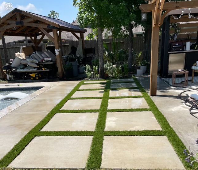 Concrete pavers with grass strips in a backyard; gazebo, pool, and bar in background.