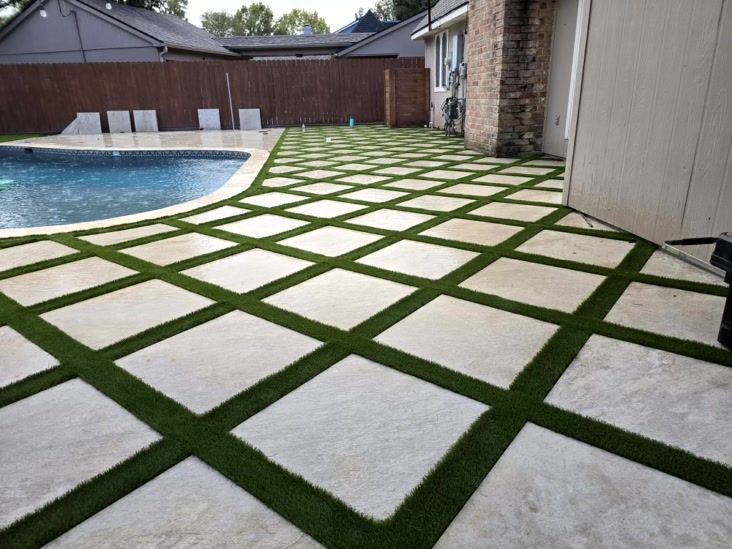 Patio with concrete squares and artificial turf, next to a swimming pool.