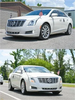 White Cadillac sedan with small American flags displayed, photographed from front and side outdoors.