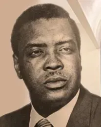 Black-and-white portrait of a man in a suit and tie, facing slightly to the side with a serious expression.