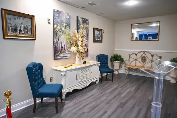 Elegant waiting room with blue chairs, white cabinet, floral arrangement, and gray wood flooring