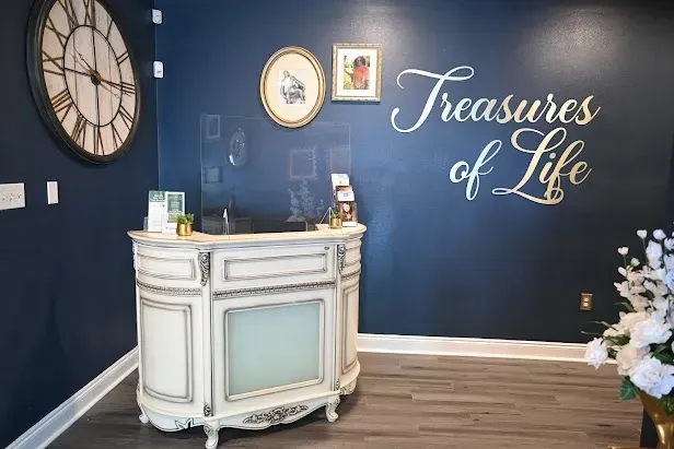 Blue wall with “Treasures of Life” script, clock, and white decorative cabinet in a stylish room