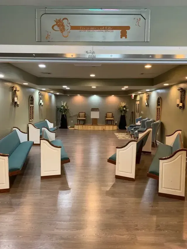 Empty community room with rows of white-and-blue chairs and wood floor under recessed lights