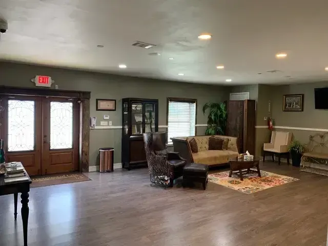 Spacious lobby with hardwood floor, seating area, double doors, and soft overhead lighting.