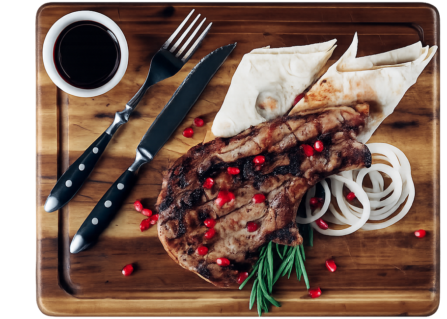 Bistecca alla griglia con rosmarino, anelli di cipolla, pane piatto e una ciotolina di salsa su un tagliere di legno con coltelli e forchette.