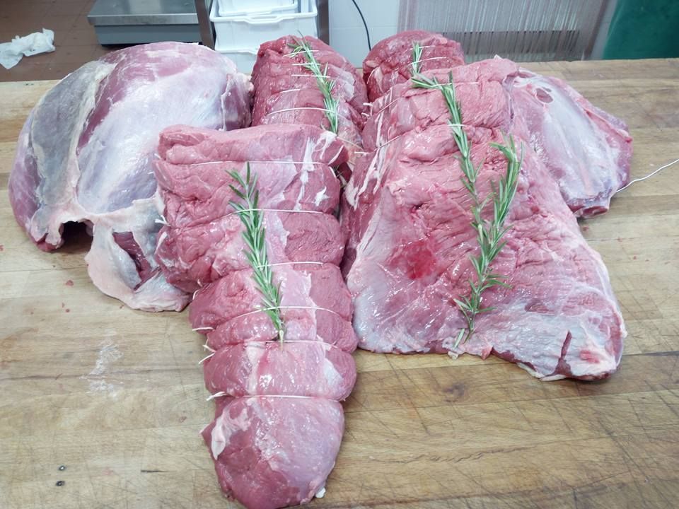 Diversi pezzi di maiale crudo legati con spago verde su un tagliere di legno