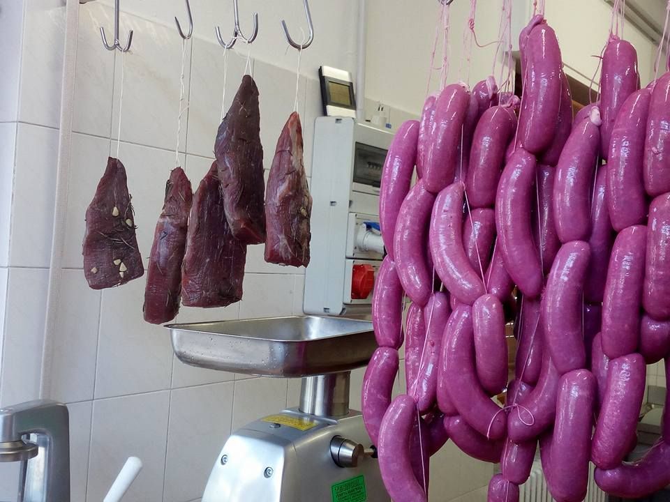 In una macelleria sono appesi diversi tipi di salumi, tra cui salame scuro e salsicce rosa.