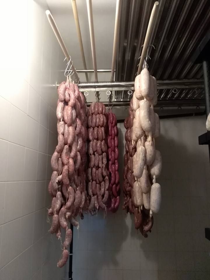 Bulbi d'aglio intrecciati e cipolle rosa appesi in una cucina piastrellata